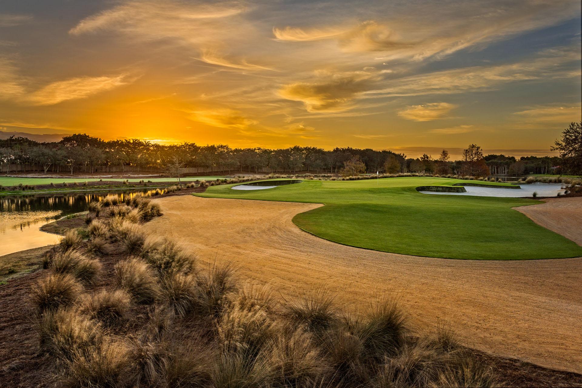 A well maintained fairway at sunset surrounded by a sandy rough