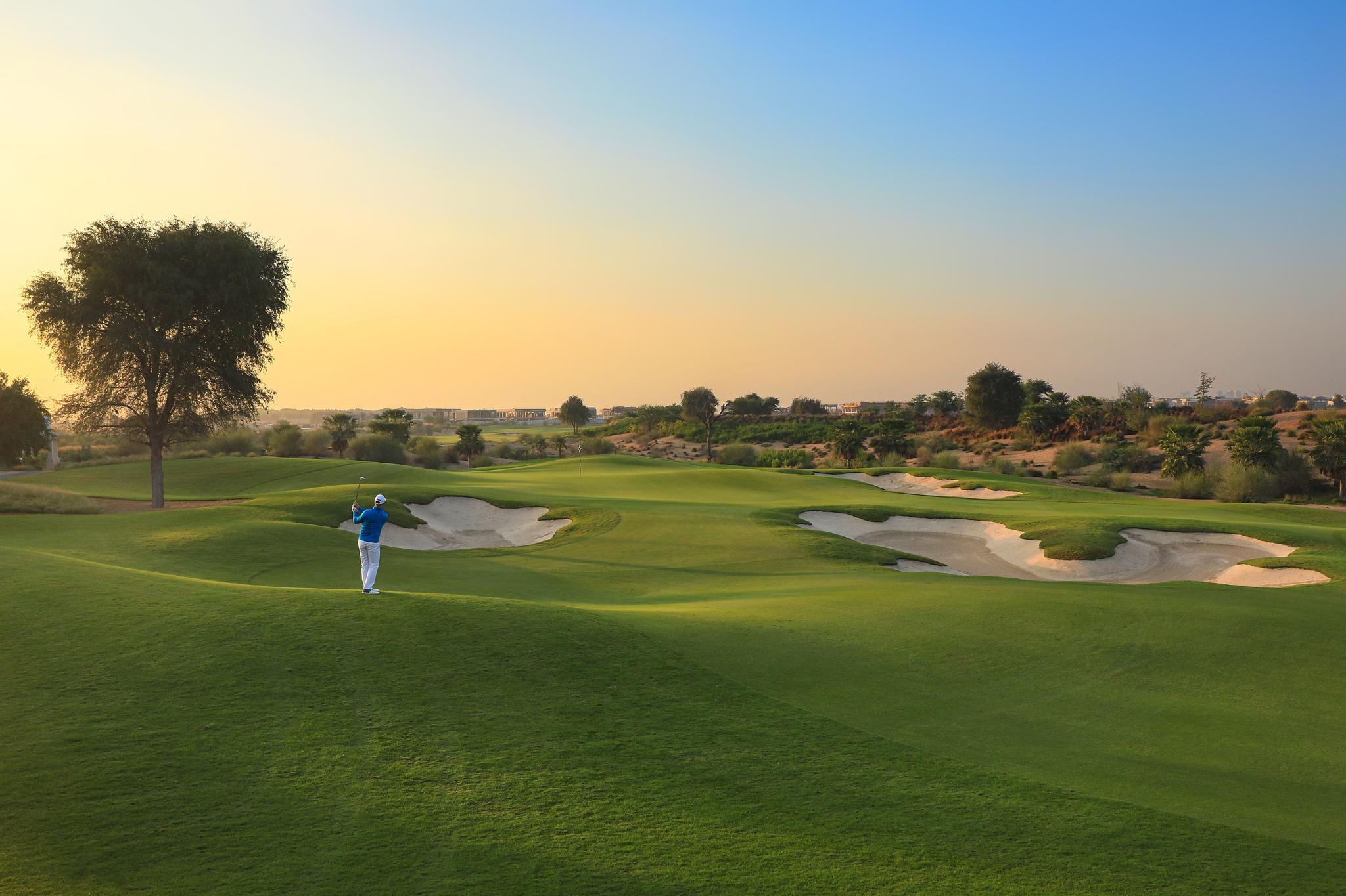 A well maintained fairway nestled with sand bunkers under clear skies