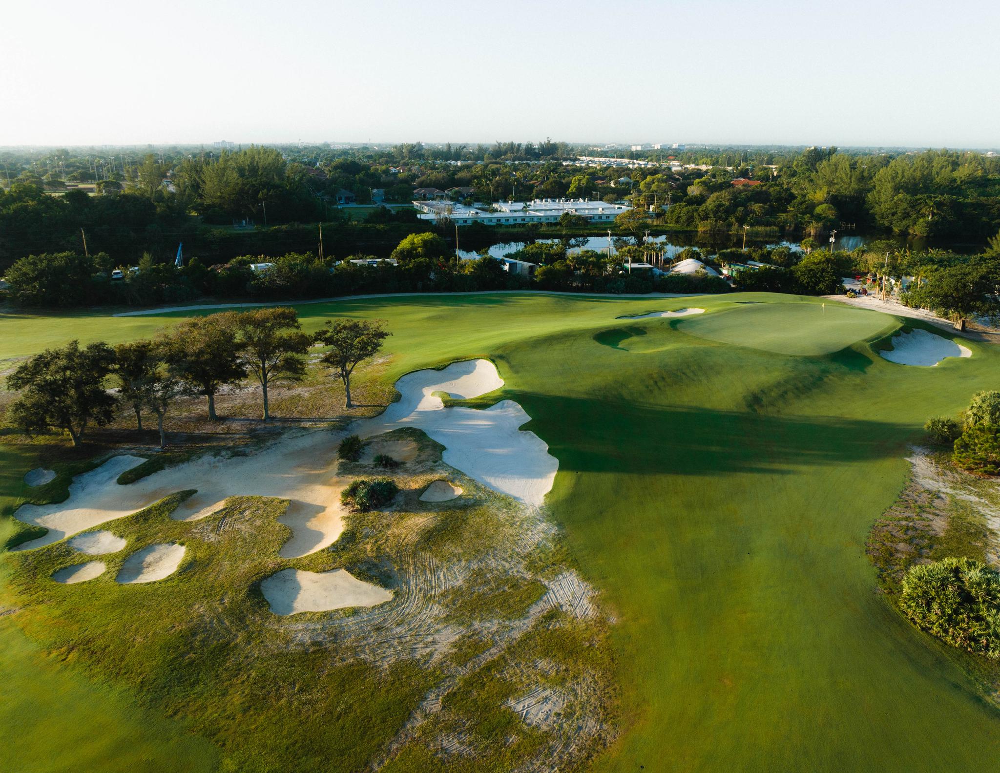 A well maintained fairway nestled with sand bunkers leading to a smooth green