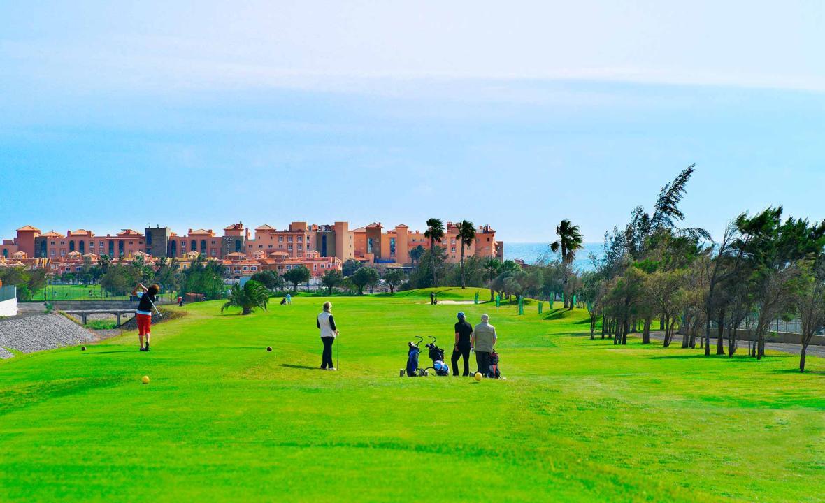 Fourball teeing off to a wide open fairway with the resort in the background