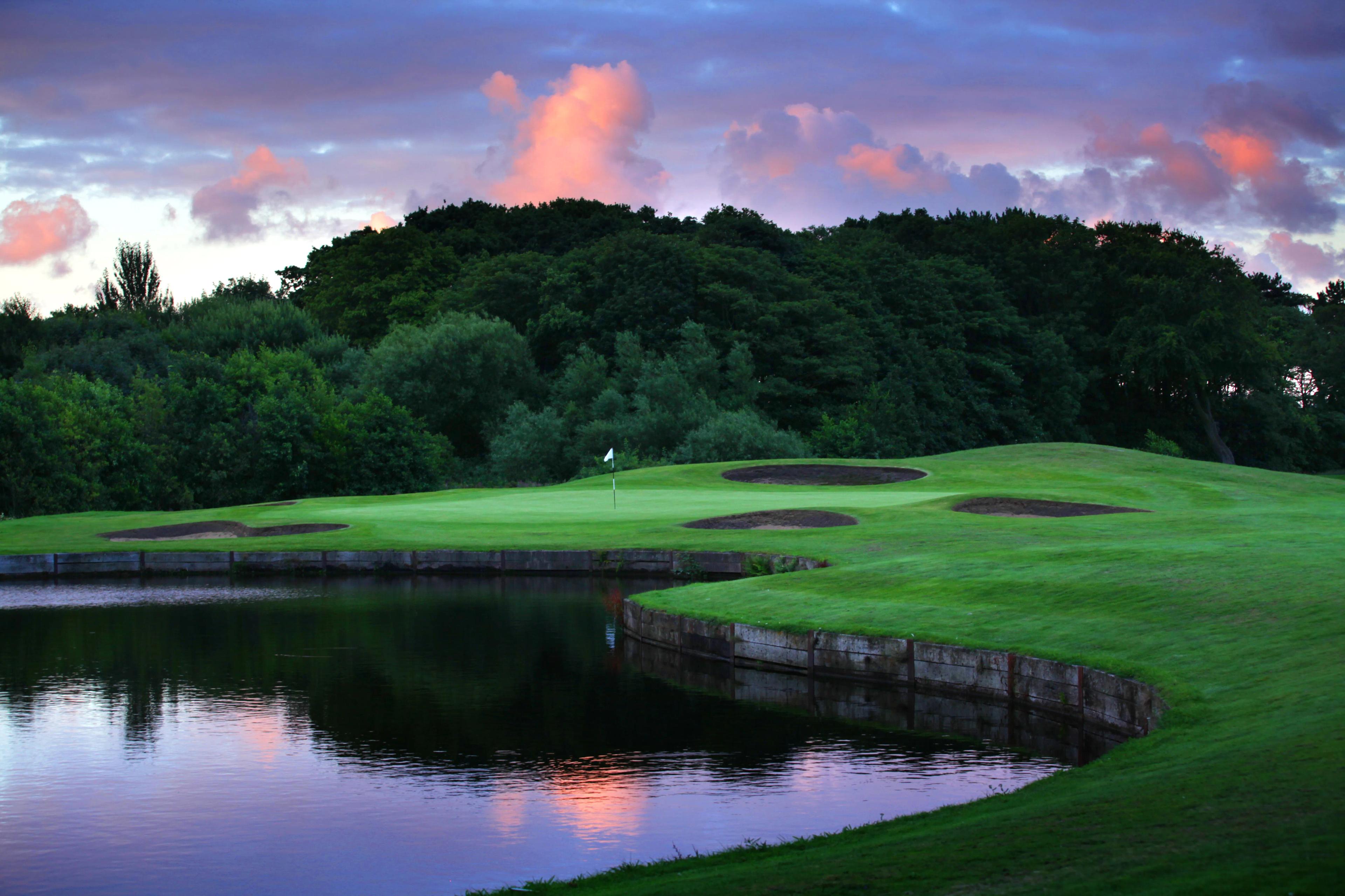 Panoramic view of a smooth green sandwiched between sand bunkers and a water hazard