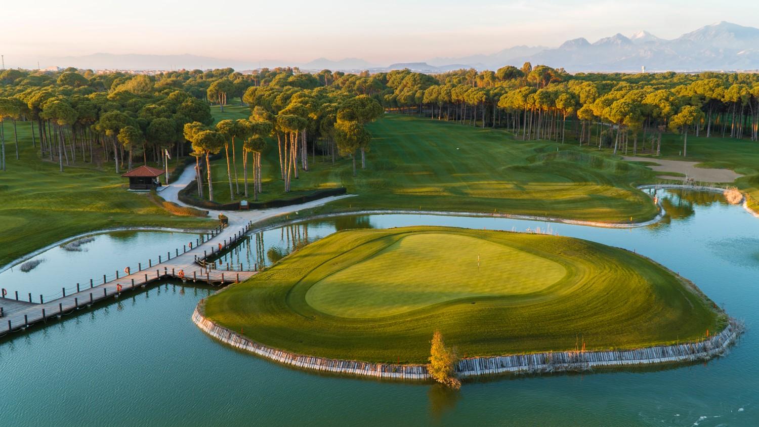 Aerial view of an island green and tree-lined fairway at Sueno Golf Club