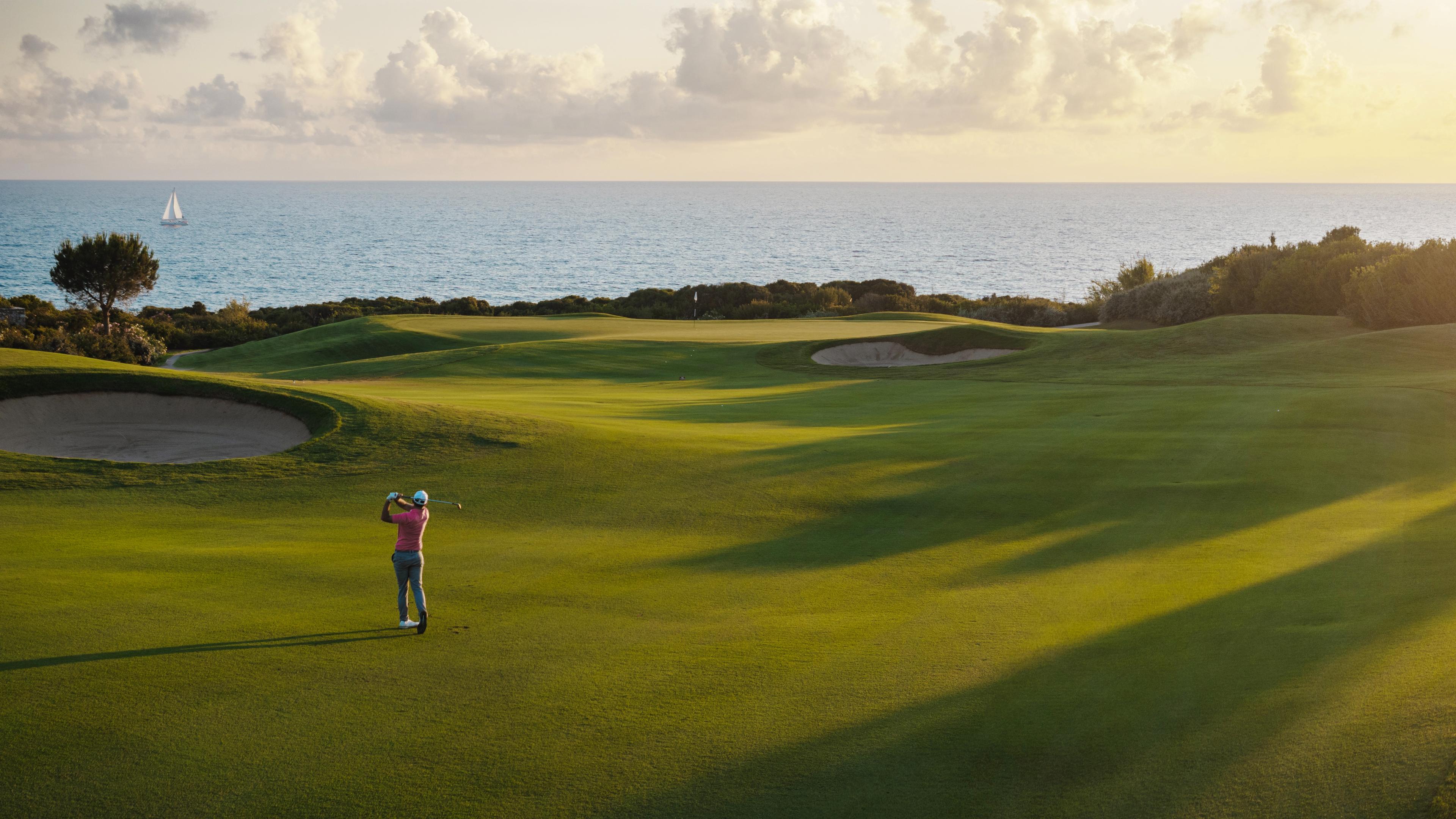 Golfer on a well maintained coastal fairway nestled with sand bunkers