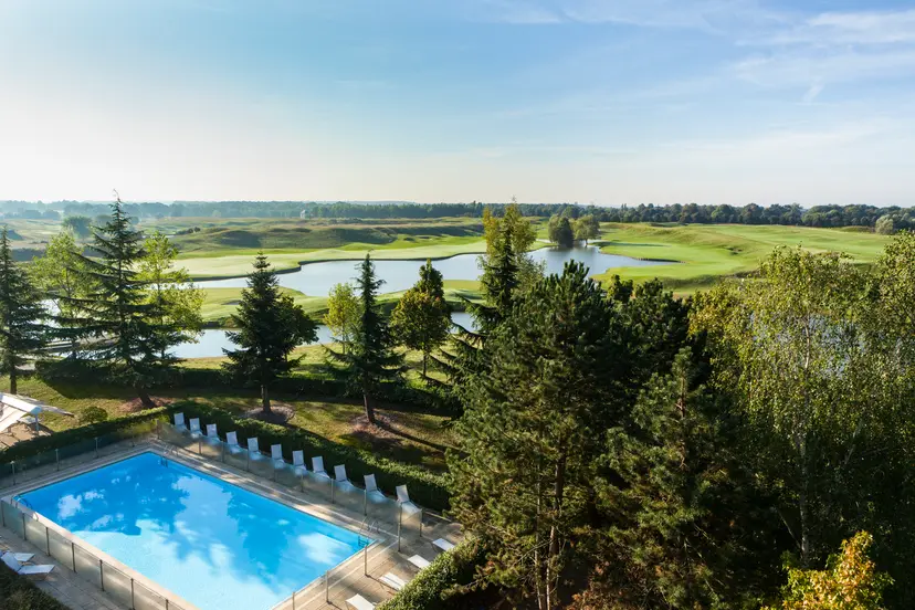 The outdoor swimming pool at Novotel Saint Quentin en Yvelines overlooking the neighbouring golf course