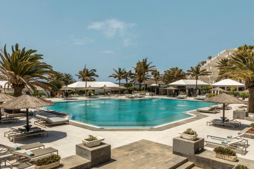 Outdoor swimming pool lined with sunbeds at Paradisus Salinas Lanzarote